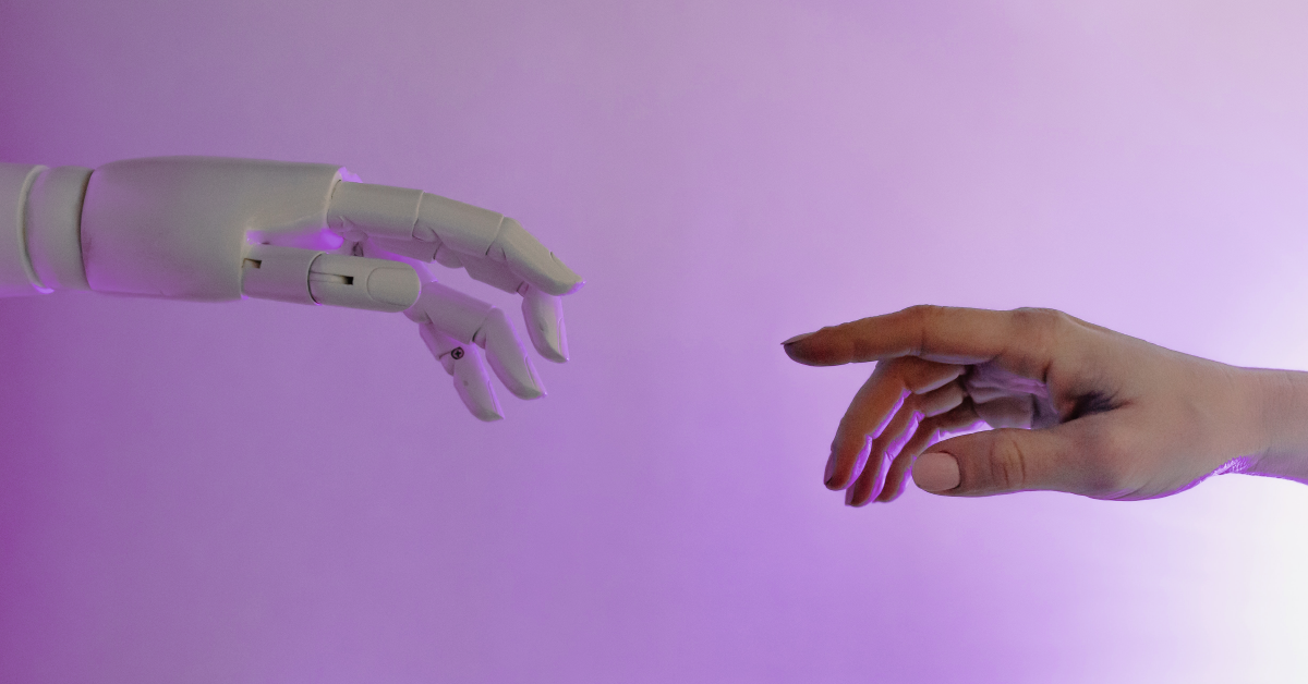 A robot hand on the left reaches out toward a human hand. They each have raised index fingers.