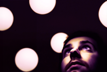 Image shooting up of a series of white dots and an close-up image of a bearded man looking outward.